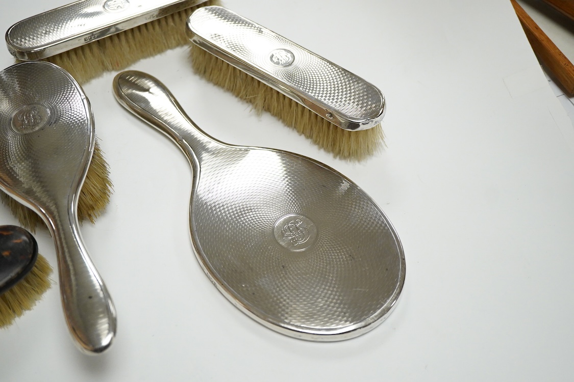 A George V seven piece silver mounted toilet set by Charles Henry Dumenil, comprising a hand mirror, four brushes, a glass toilet jar and button hook, London, 1911/12 & 18, together with one other silver mounted toilet j